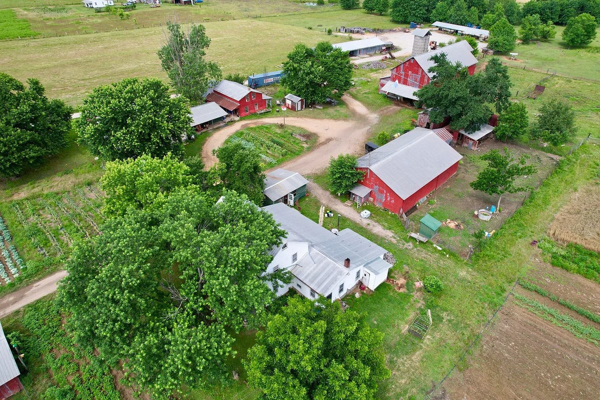 Aerial view of Amish farm compound with white house, red barns, and silo in Randolph, Mississippi