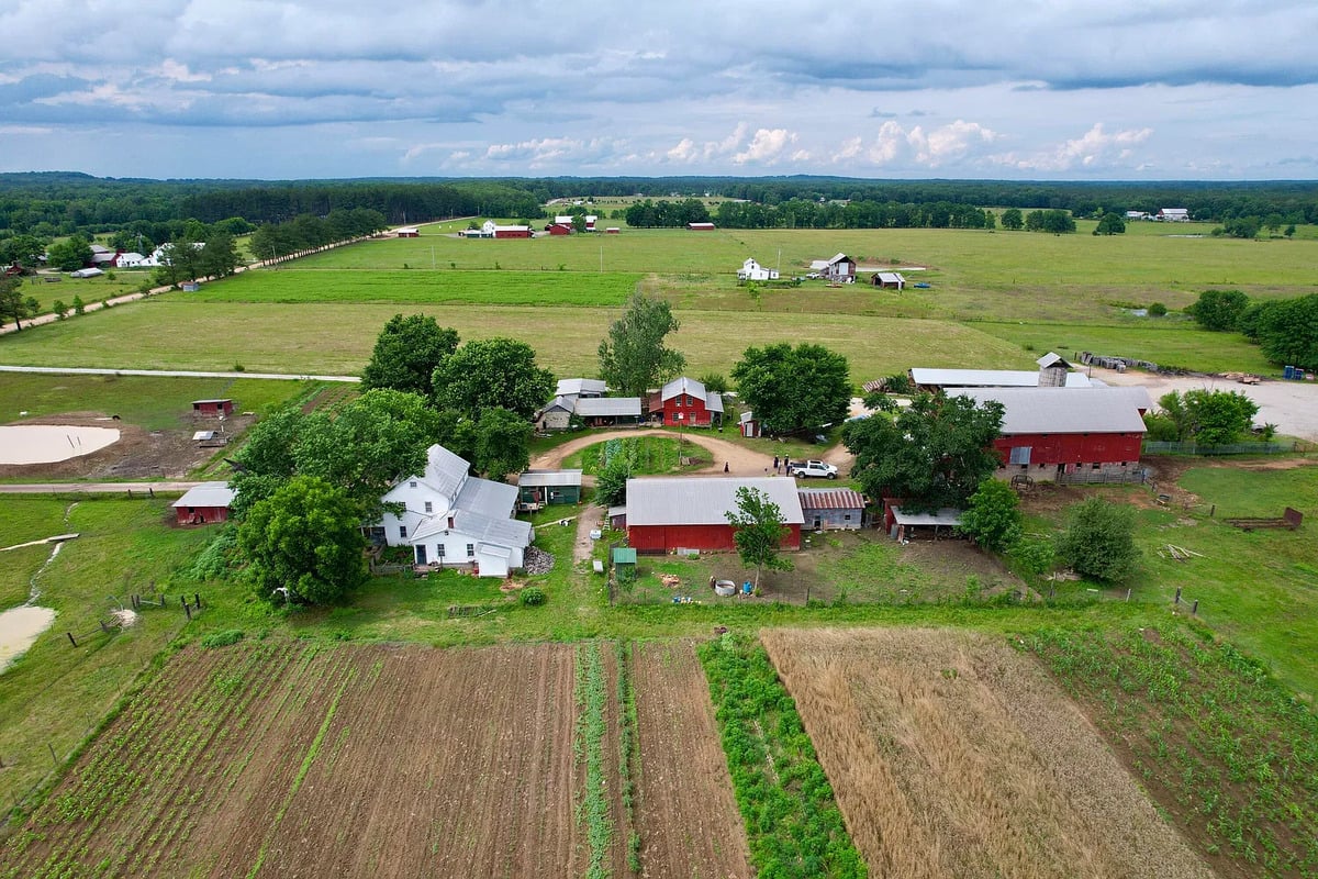 Aerial view of Amish farmstead with field plots and red barns in Randolph, Mississippi
