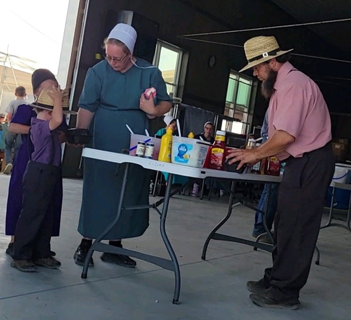 An Amish family at a condiment table at the food stand