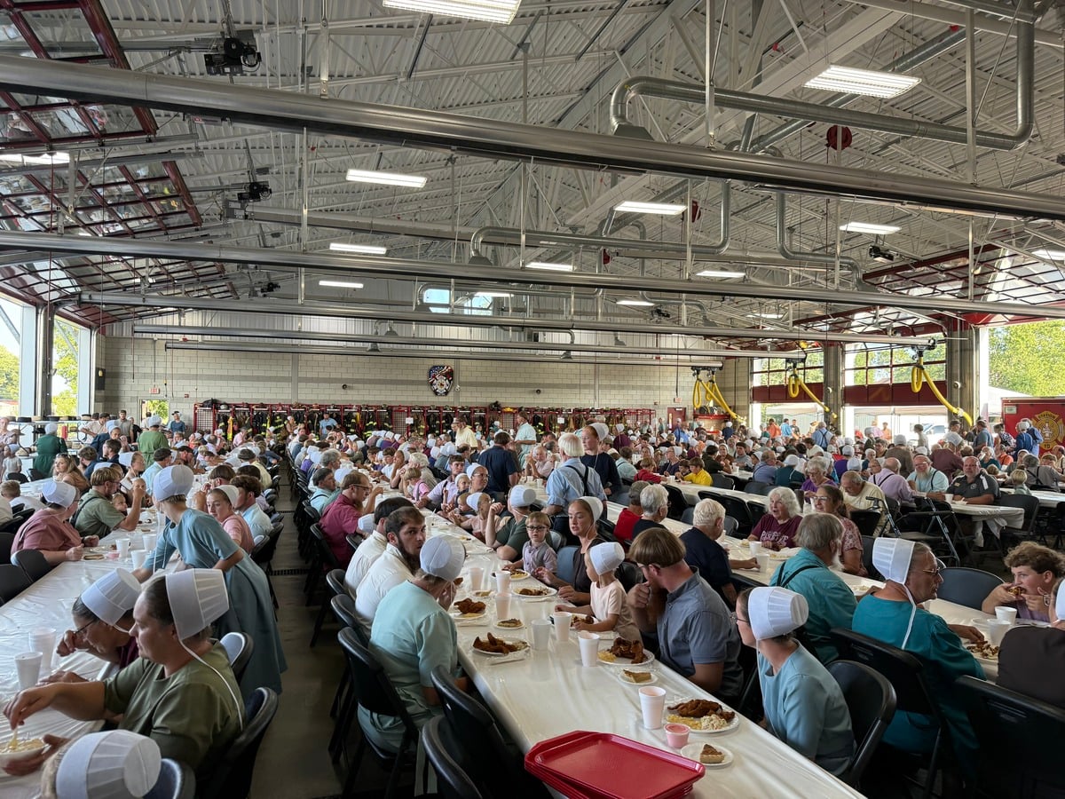 Amish families eating at long tables inside the Topeka Fire Department station