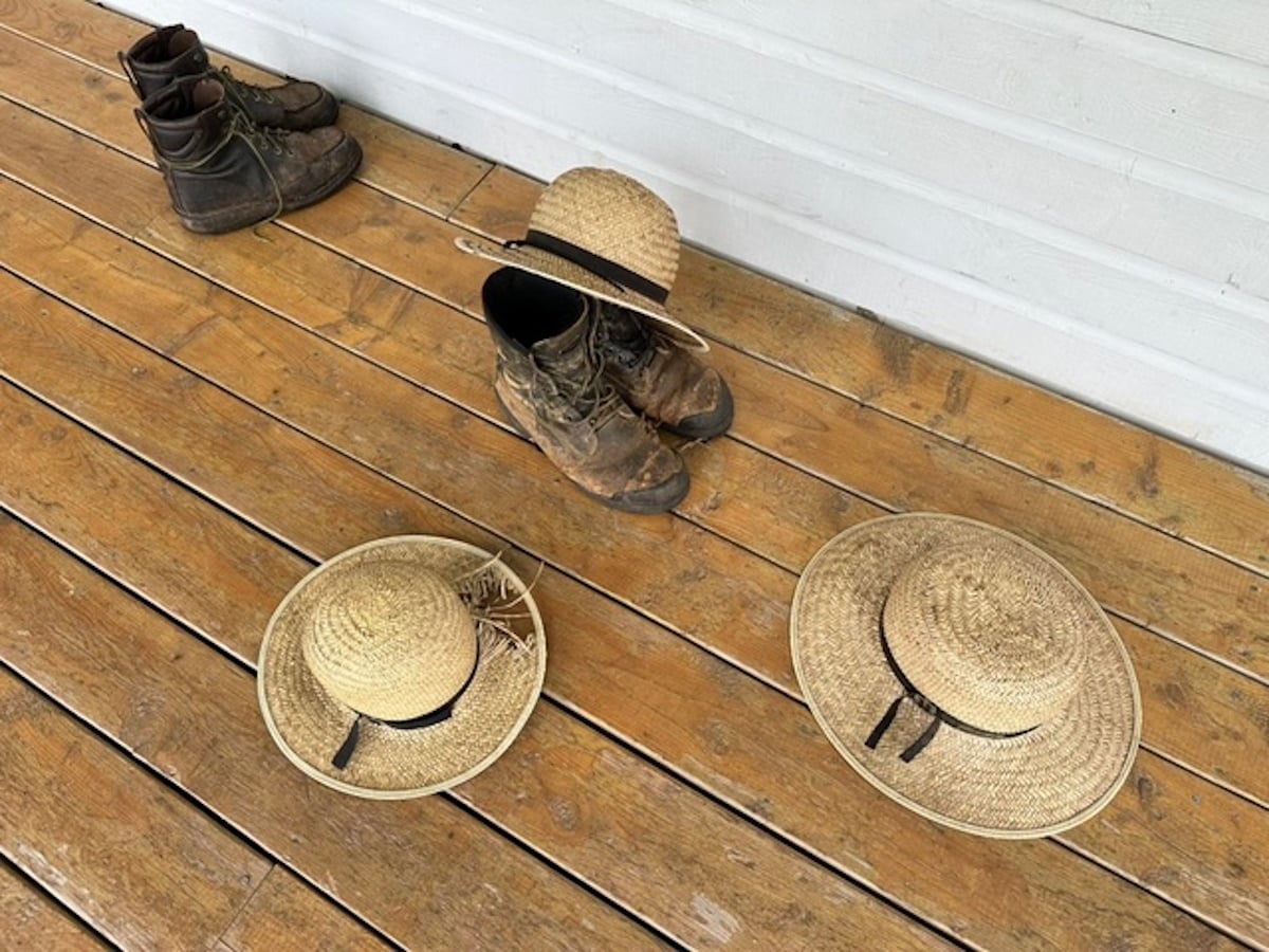 Amish straw hats and work boots left on the wooden porch of a home on Prince Edward Island, Canada