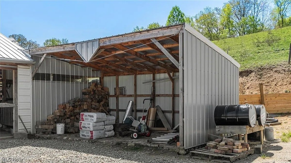 Open lean-to outbuilding with firewood stacked inside at Amish homestead Cumberland Ohio