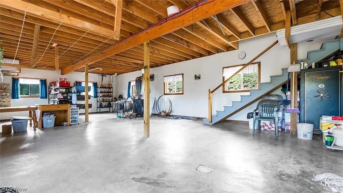 Massive lower-level workshop in Amish-built home in Cumberland Ohio with exposed wood beam ceiling and concrete floor