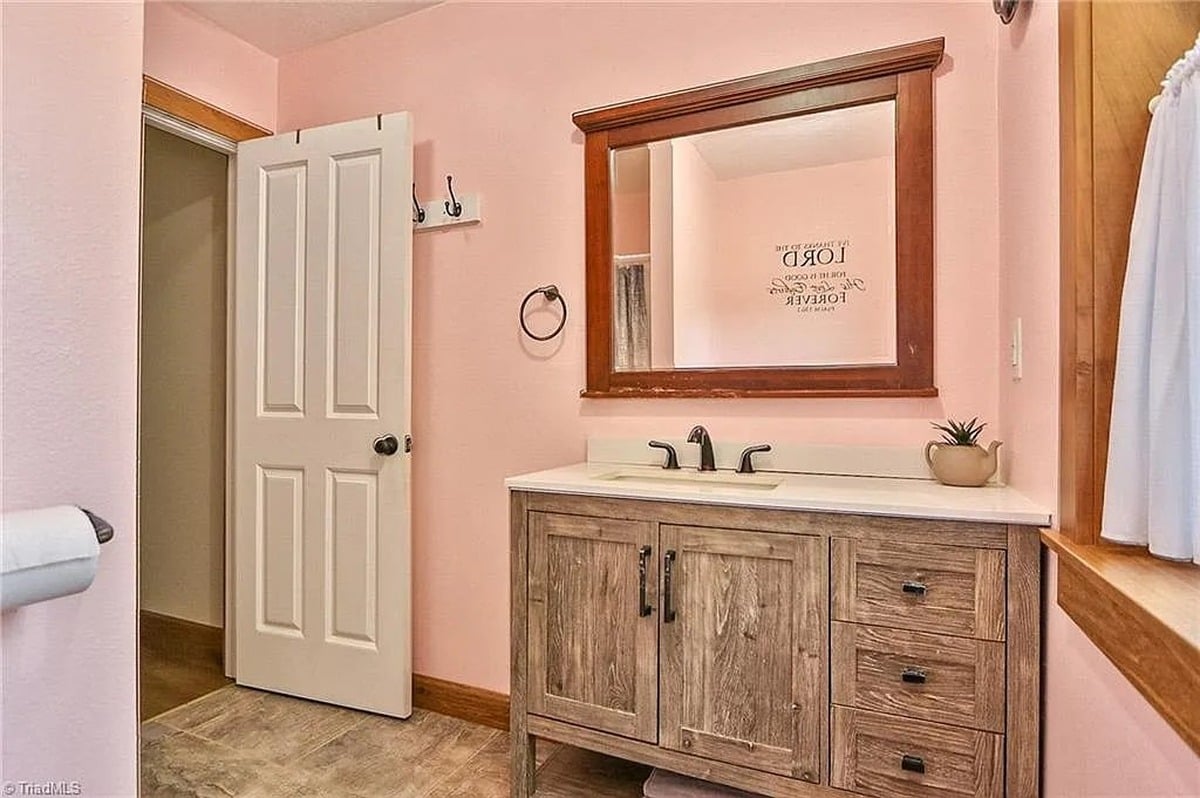 Pink bathroom with rustic wood vanity and The Lord is Good scripture mirror decal in Amish home, Hamptonville, NC