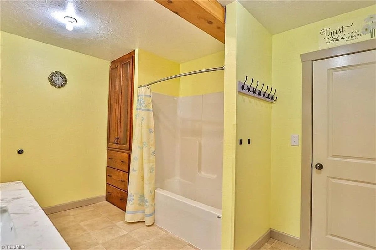 Bathroom tub and shower with wood storage cabinet and Trust in the Lord scripture decal in Amish home, Hamptonville, NC