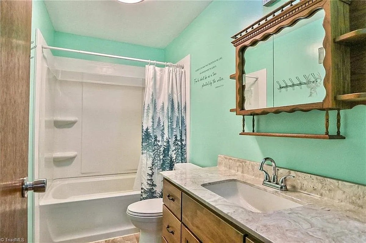 Teal bathroom with wooden medicine cabinet mirror and scripture wall decal in Amish home, Hamptonville, NC