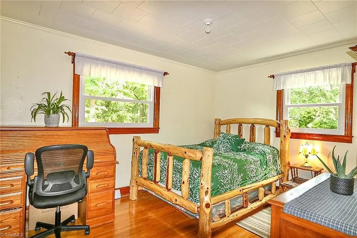 Upstairs bedroom in Amish home, Hamptonville, NC with log-frame bed, roll-top desk, and hardwood floors