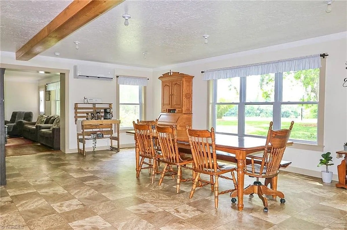 Second angle of dining room in Amish home in Hamptonville, NC showing table, hutch, large windows, and view to yard