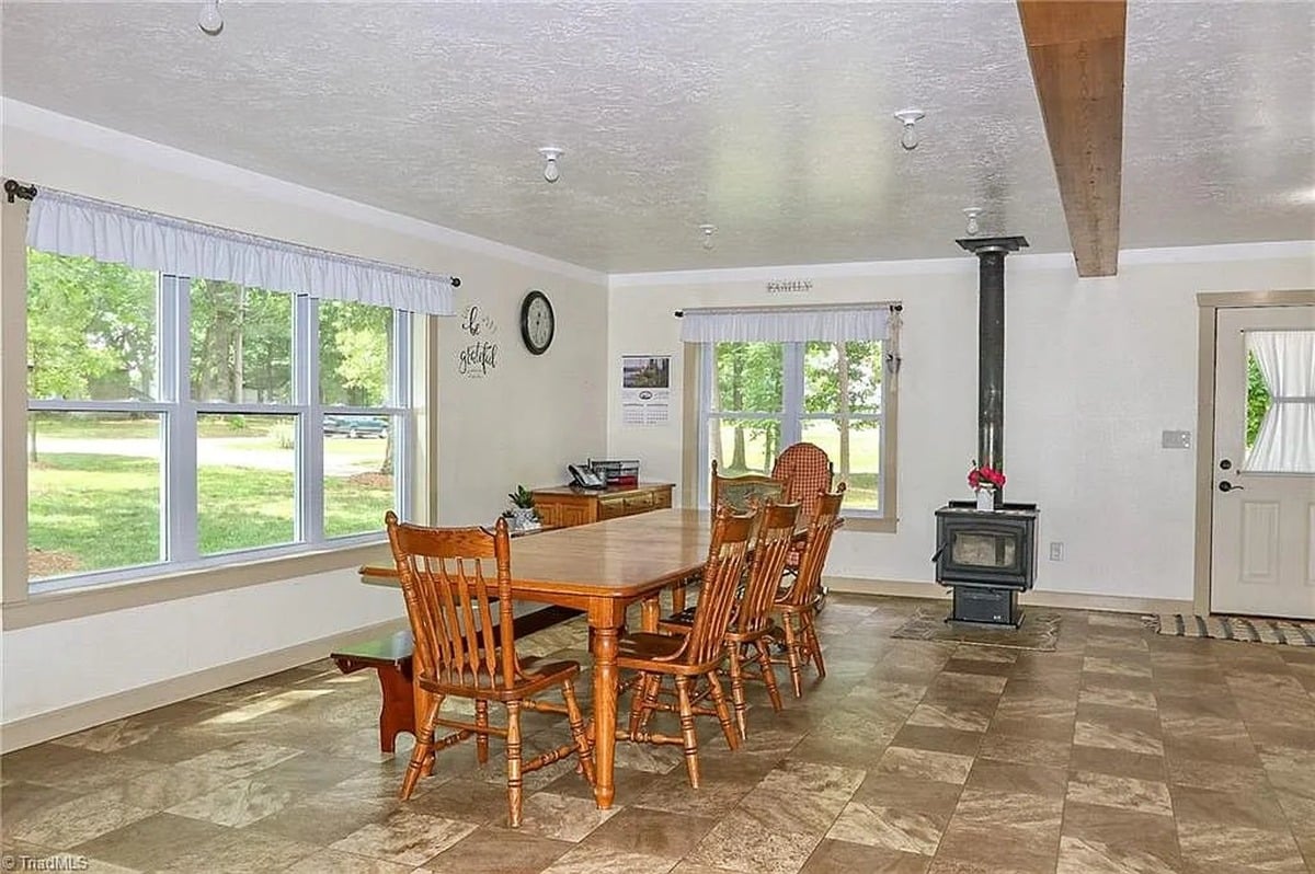 Dining room of Amish home in Hamptonville, NC with wood table, bench seating, and black wood burning stove