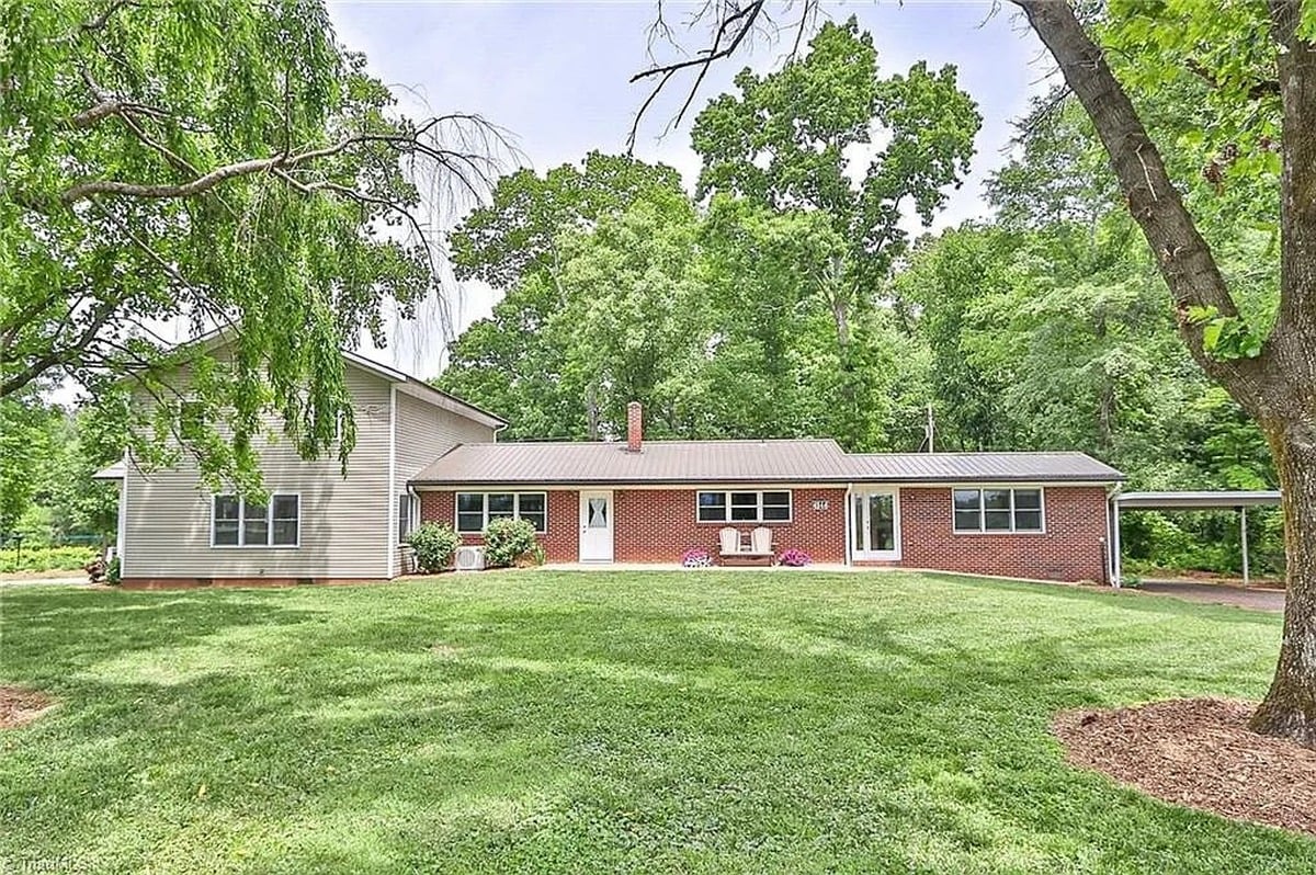 Rear exterior of Amish home in Hamptonville, North Carolina showing original brick ranch section and newer vinyl-sided addition