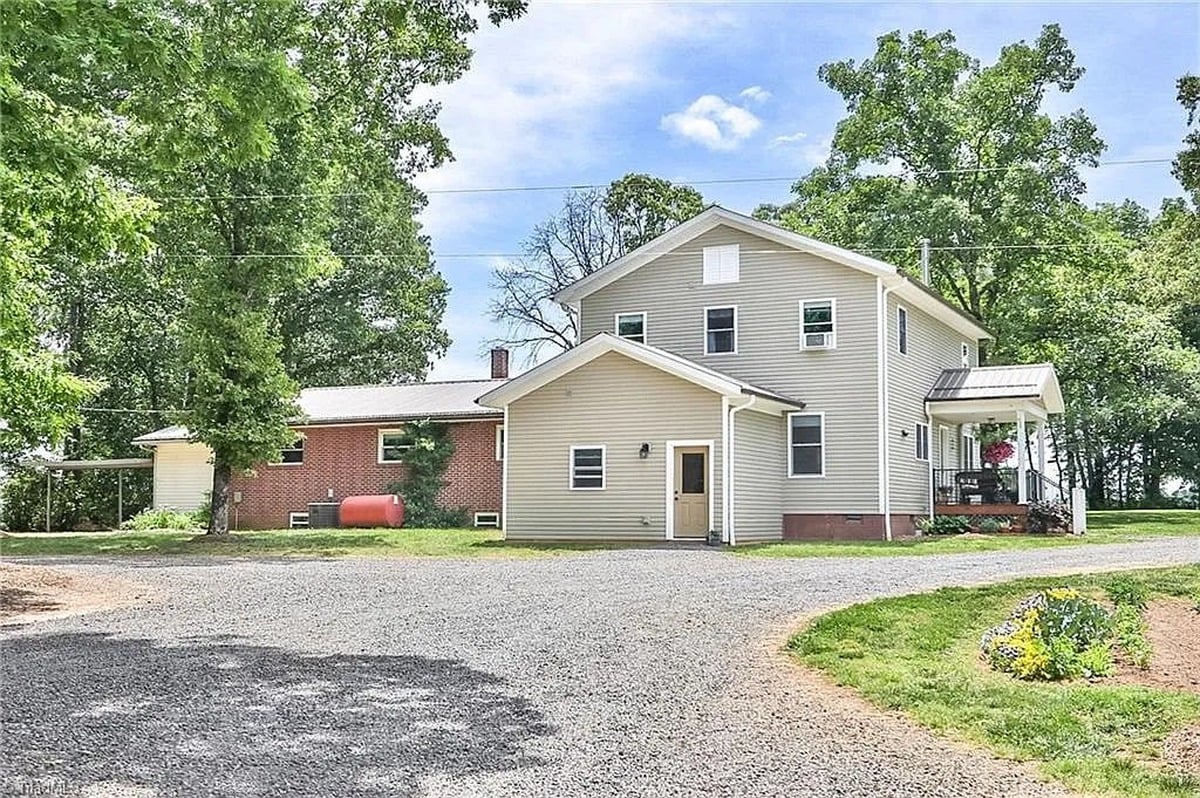 Amish home for sale in Hamptonville, North Carolina showing two-story addition and original brick ranch with circle gravel drive