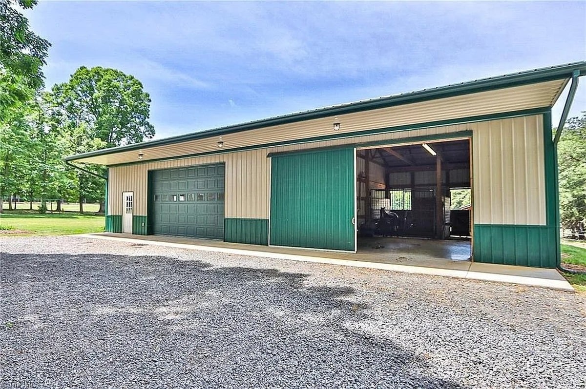 Exterior of green metal garage and barn at Amish home in Hamptonville, NC with sliding door open and buggy partially visible
