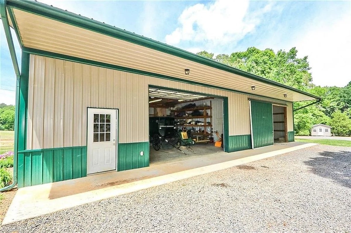 Wide exterior view of 30x60 green metal garage and barn at Amish home in Hamptonville, NC with Amish buggy clearly visible inside open bay