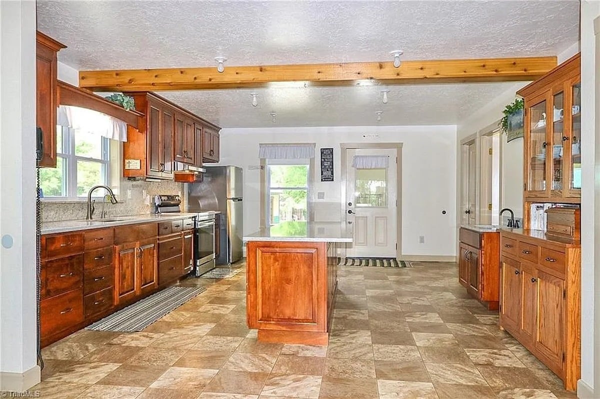 Main kitchen of Amish home in Hamptonville, NC with custom wood cabinets, center island, quartz countertops, and bare electric light bulbs on ceiling