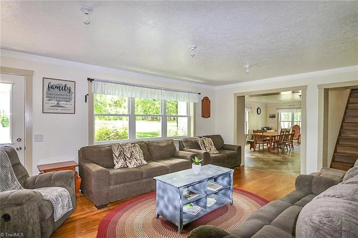 Living room of Amish home in Hamptonville, North Carolina with wood floors, sofas, and view into dining room