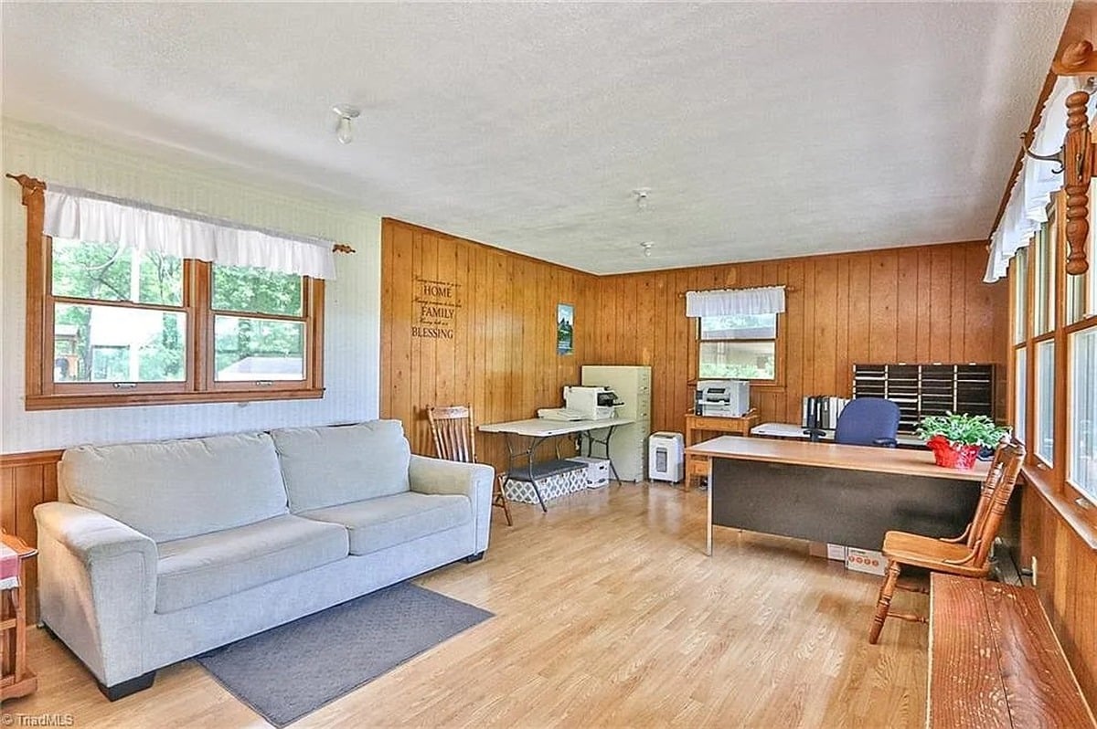 Office and sitting room in original section of Amish home in Hamptonville, NC with wood paneling, sofa, and desk