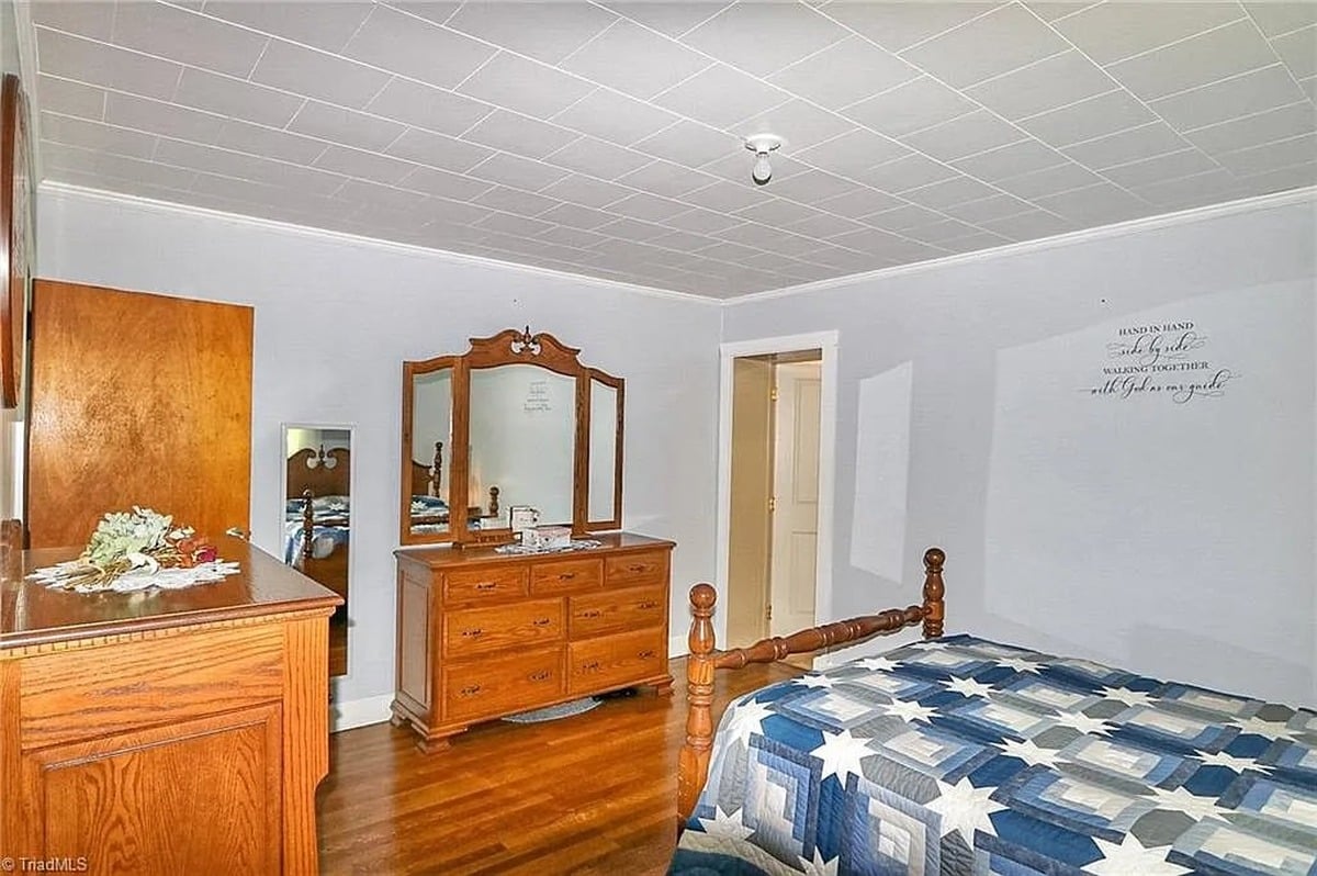 Primary bedroom of Amish home in Hamptonville, NC showing dresser with mirror and Hand in Hand scripture wall decal