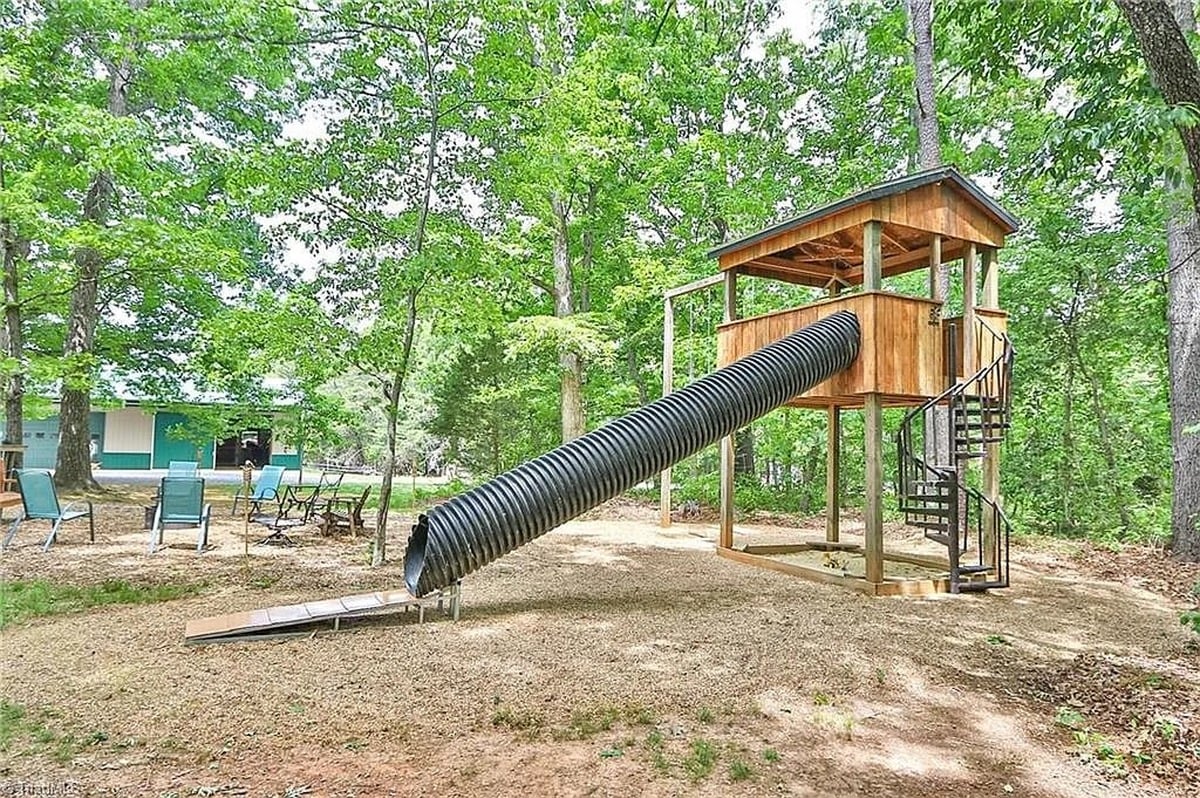 Treehouse with corrugated drainage pipe tube slide at Amish home in Hamptonville, North Carolina with fire pit area visible in background