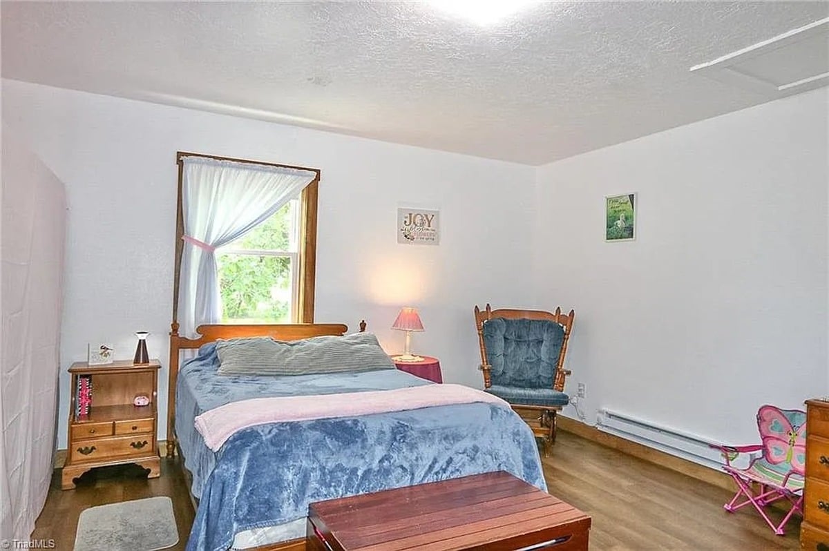 Upstairs bedroom in Amish home, Hamptonville, NC with wooden bed, rocking chair, and baseboard heater