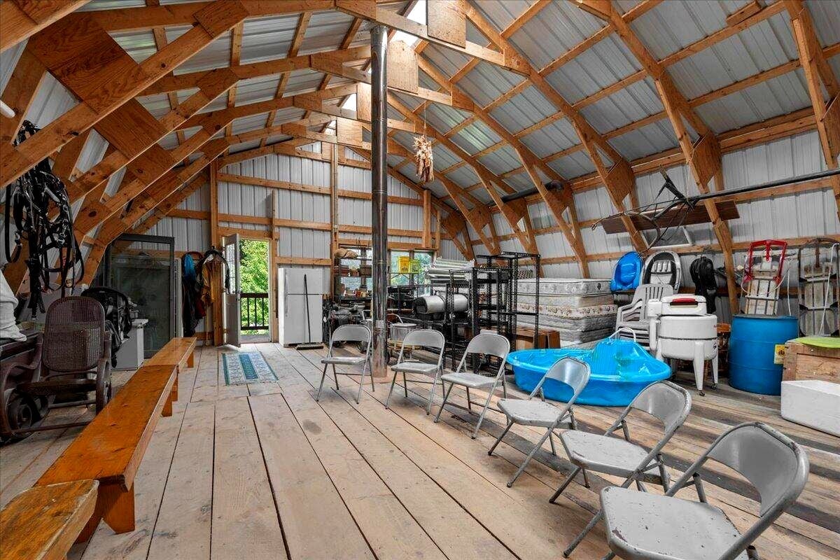 Round bale barn interior with arched timber rafters and skid steer at Amish farm, New Holstein, Wisconsin