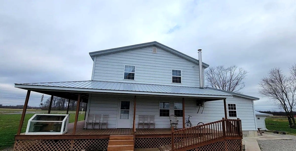 Front porch of Amish home in Vevay, Indiana with wooden deck, rocking chairs, and open farmland view