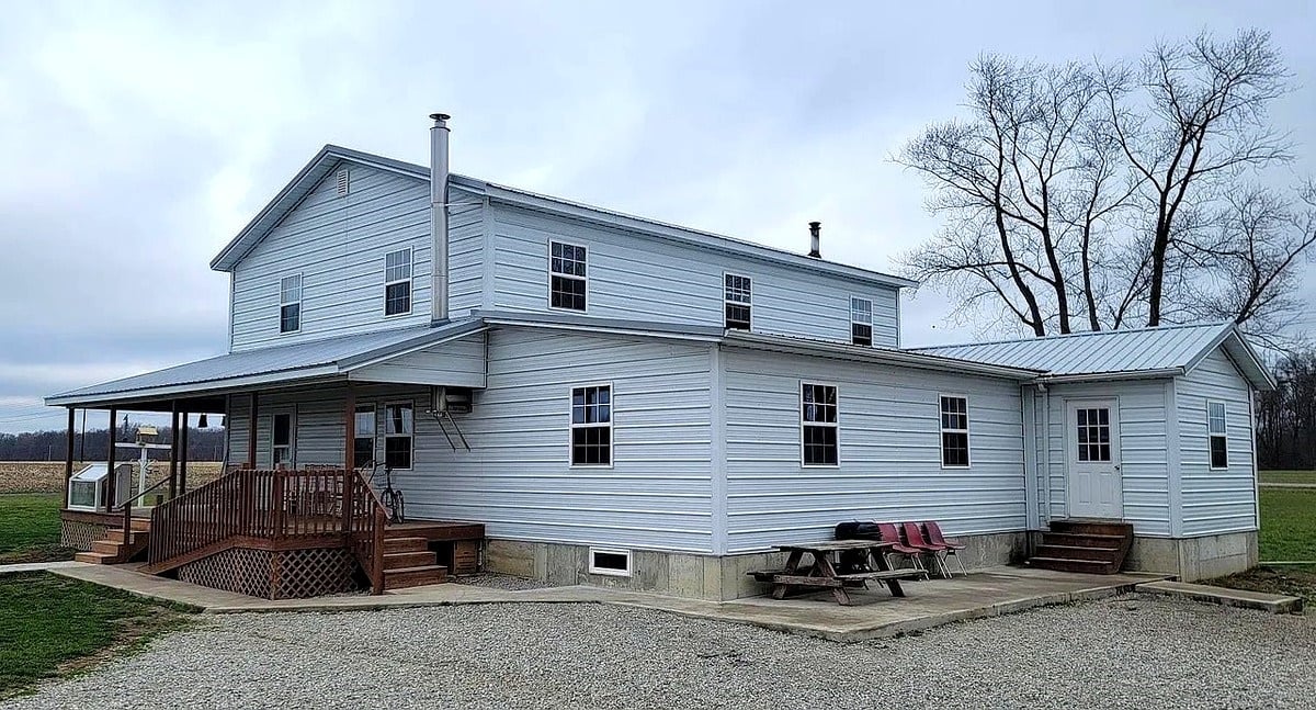 Two-story Amish home with metal roof, front porch, and flat Indiana farmland in the background, Vevay, Indiana