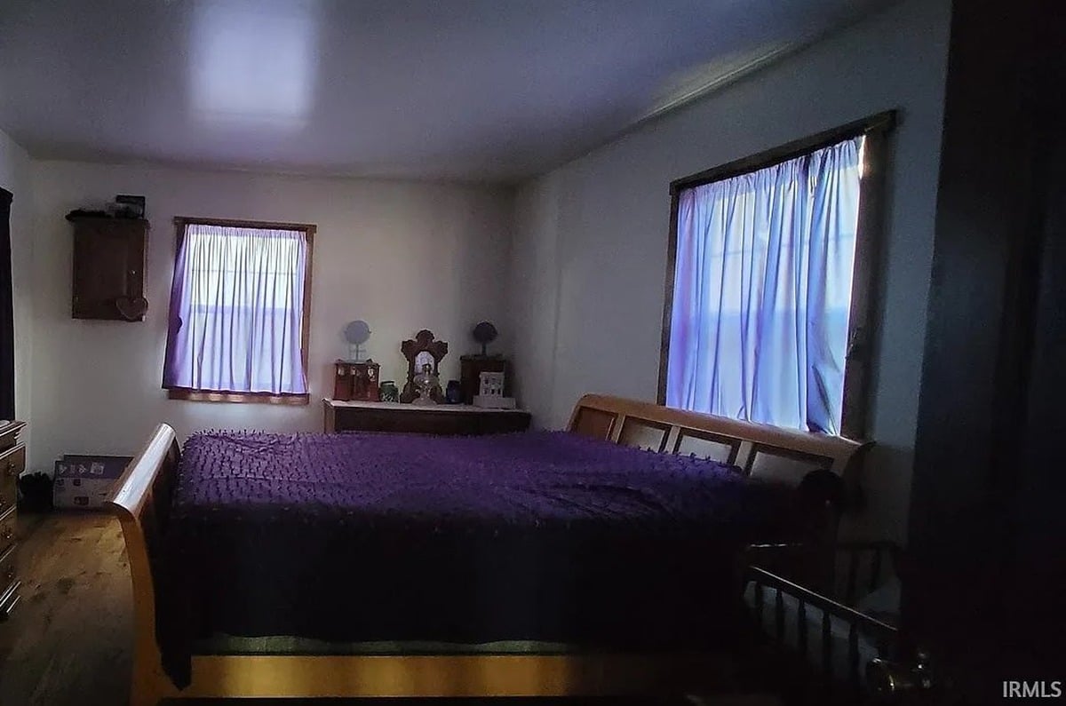 Bedroom with purple quilt and wooden bed frame inside Amish home in Vevay, Indiana