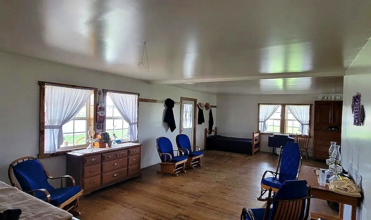 Sitting room with blue rocking chairs, dresser, and coat hooks inside Amish home in Vevay, Indiana