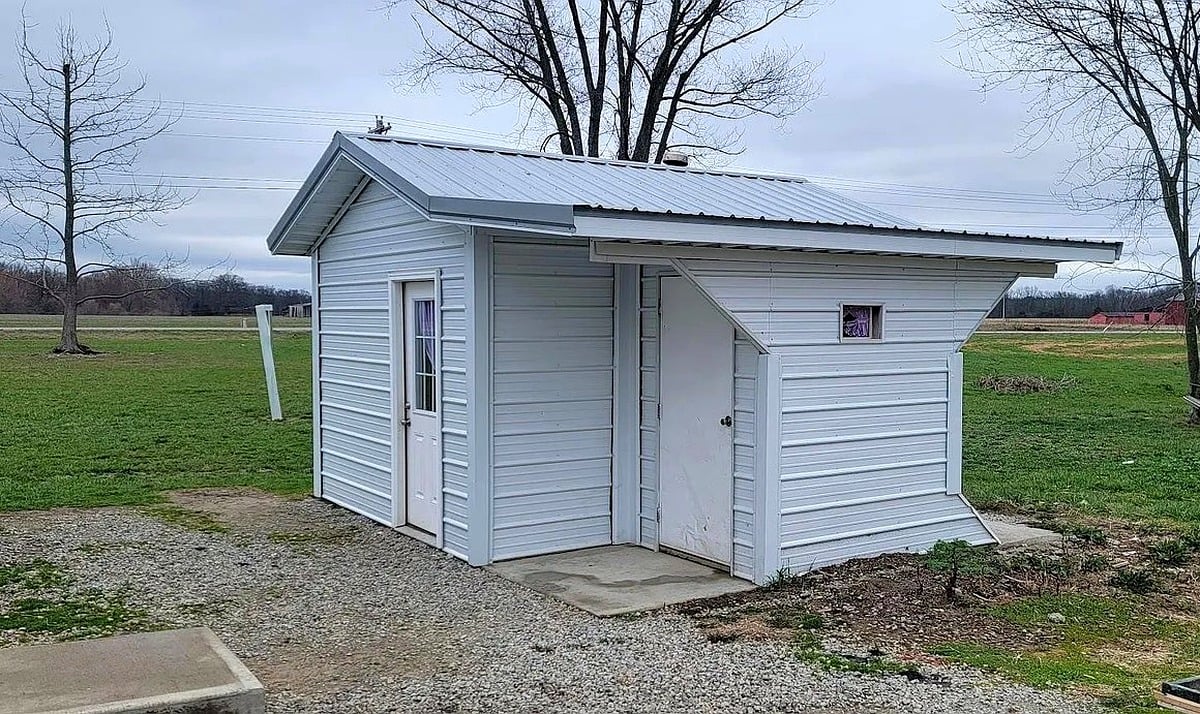 White outhouse with two doors and metal roof at Amish property in Vevay, Indiana