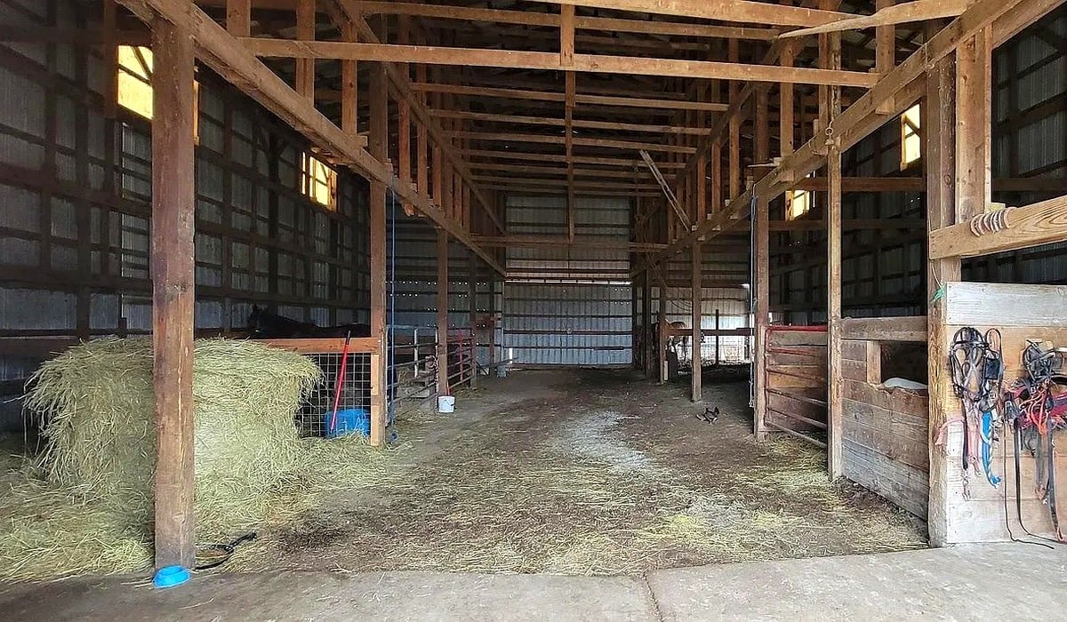 Interior of pole barn with hay bales, livestock stalls, and harness at Amish farm in Vevay, Indiana
