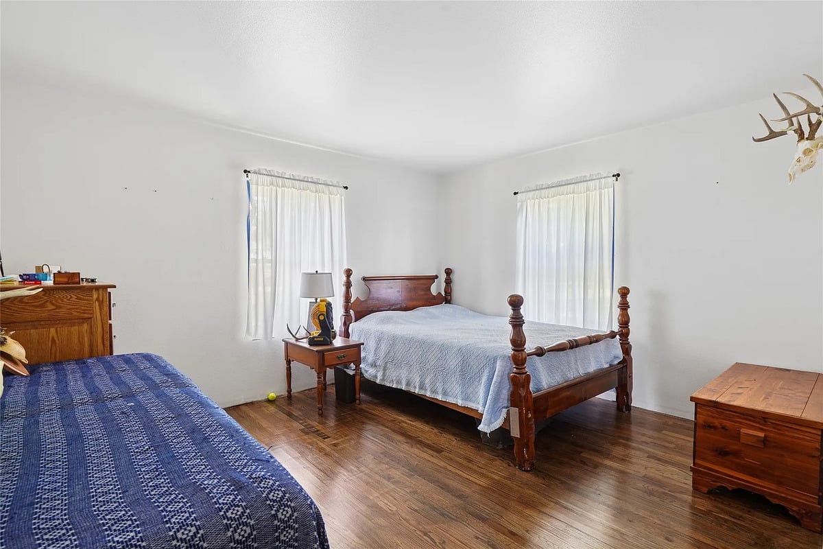Bedroom with two beds and antlers in the Winterset Amish home Amish bedroom with two beds, wooden furniture, and a set of antlers on the wall