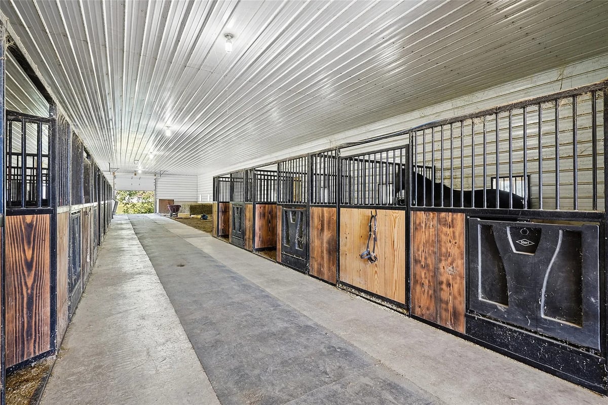 Horse barn with box stalls at the Winterset Amish homestead Interior aisle of an Amish horse barn with a row of wooden box stalls