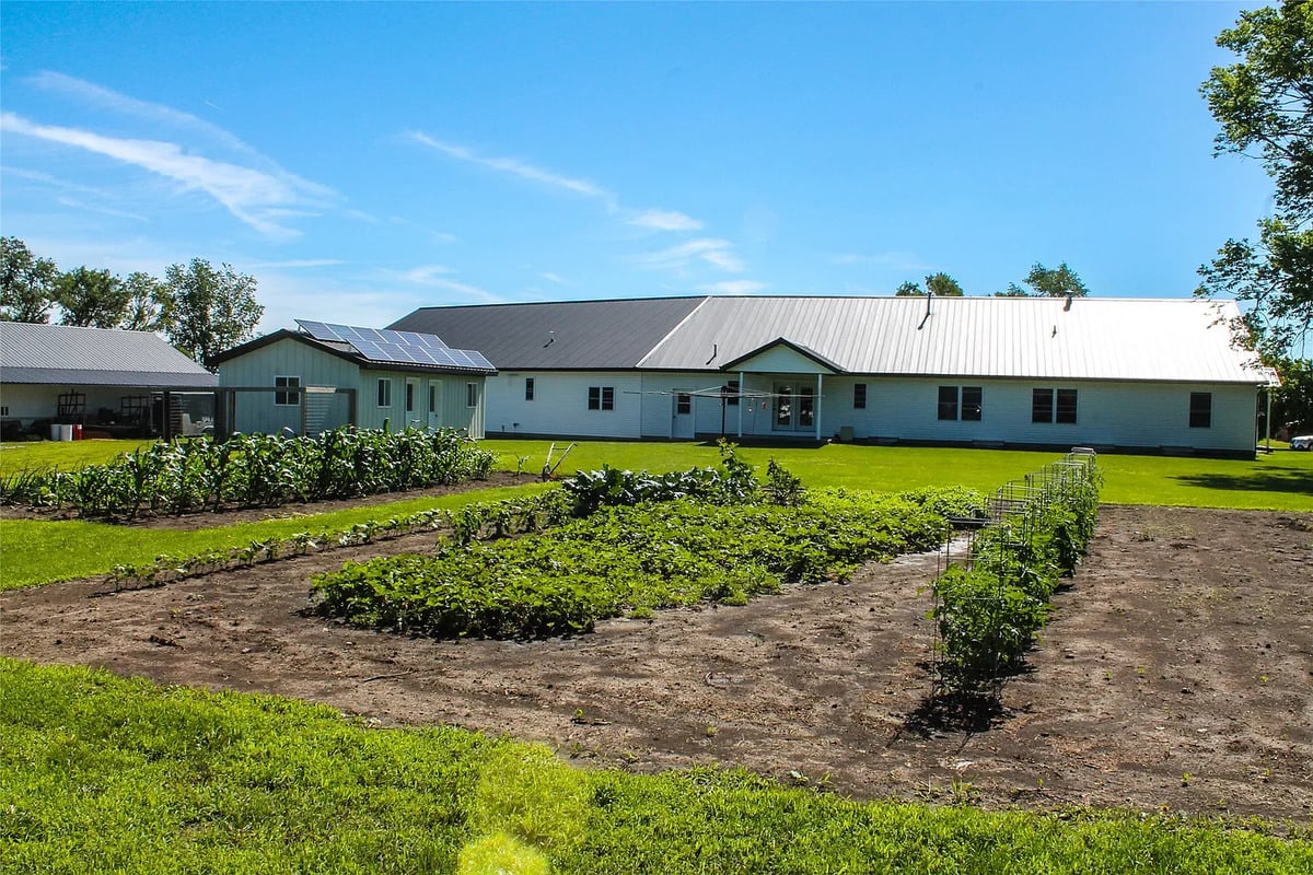 Rear of the Winterset Amish home with solar panels and gardens Rear view of Amish home with solar panels, clotheslines, and large vegetable gardens