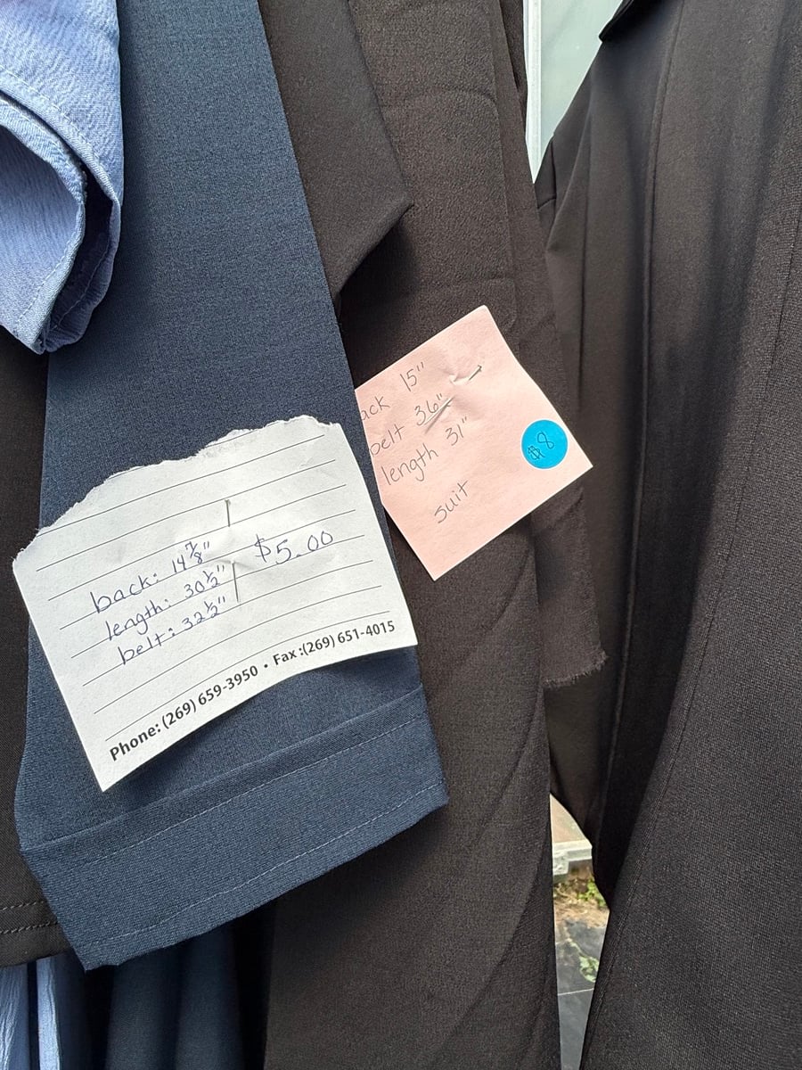 Handwritten price tags on men's Amish suits reading five and eight dollars