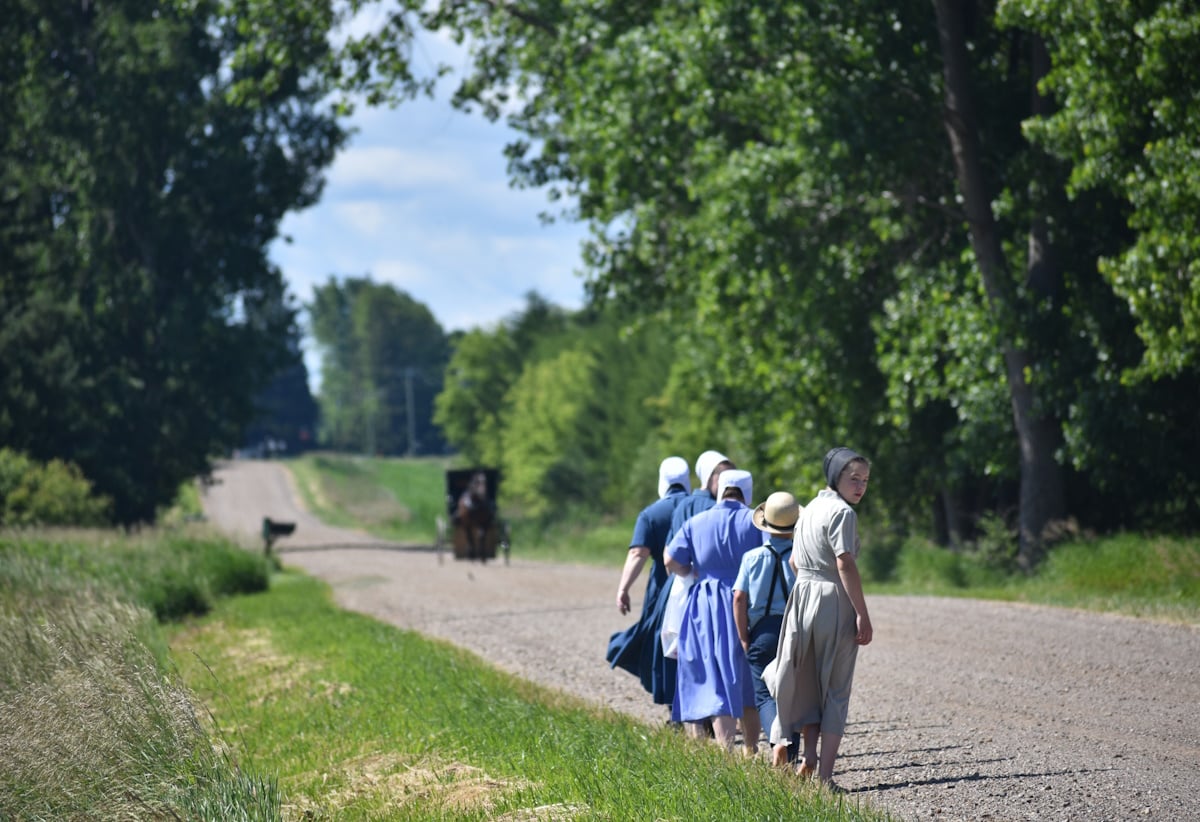 Amish people on a Michigan country road Amish people walk along a gravel country road in rural Michigan as a horse and buggy approaches in the distance