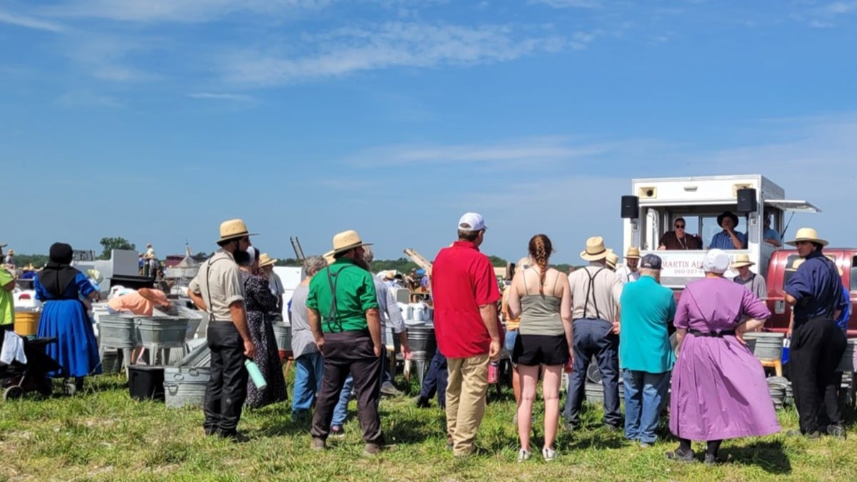 Amish and English buyers gathered around an auctioneer's truck