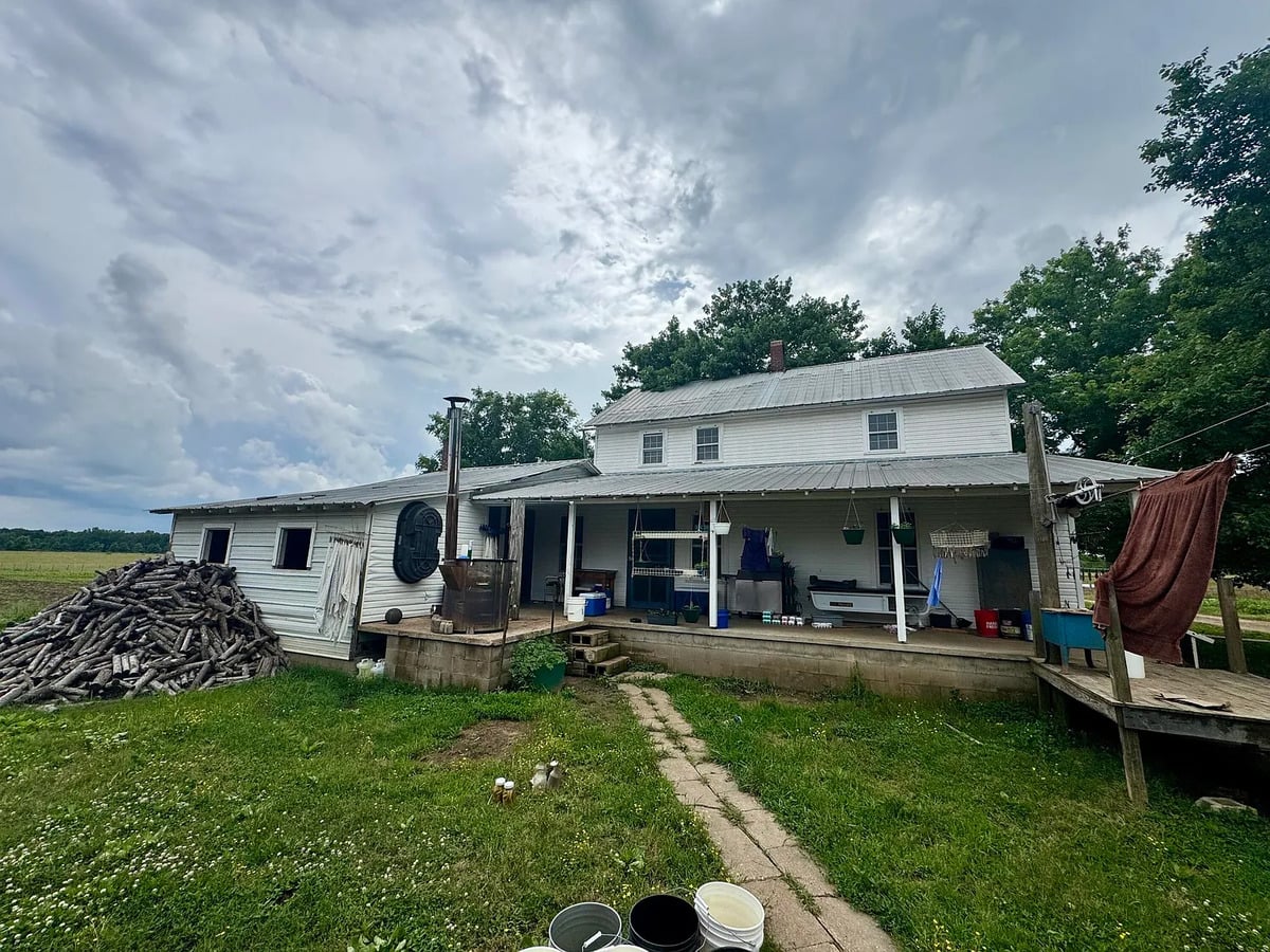 Back porch of Amish home with wringer washer, hanging baskets, and pile of wood slabs, Randolph Mississippi