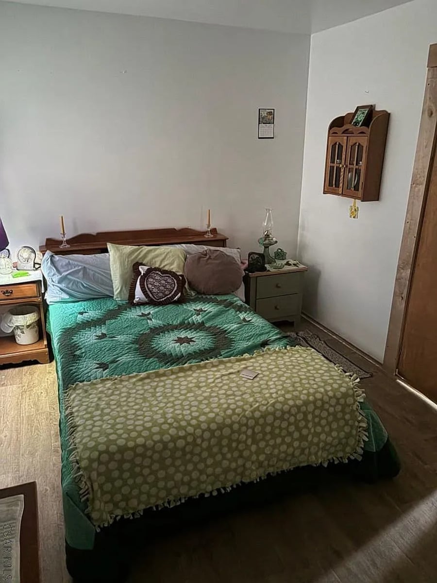 Bedroom with a green star-pattern quilt and an oil lamp in a Punxsutawney, PA Amish home