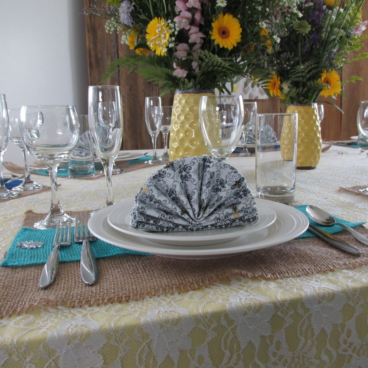 Bridal table place setting with a bee-print folded napkin and burlap placemat