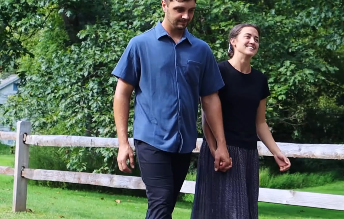 Ben and Rose walking and smiling beside a fence
