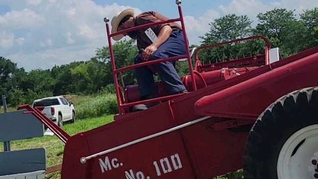 A bidder climbing on a red McCormick implement to inspect it