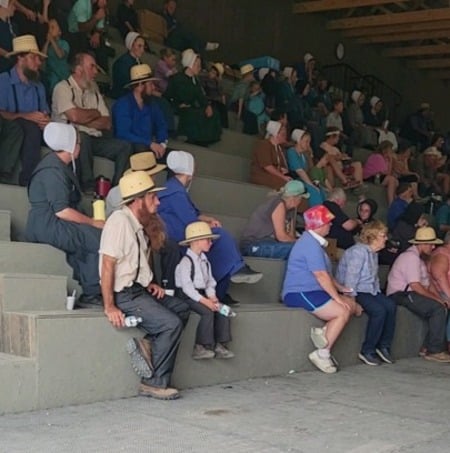 Amish and English auction-goers seated in bleachers at the horse and tack sale
