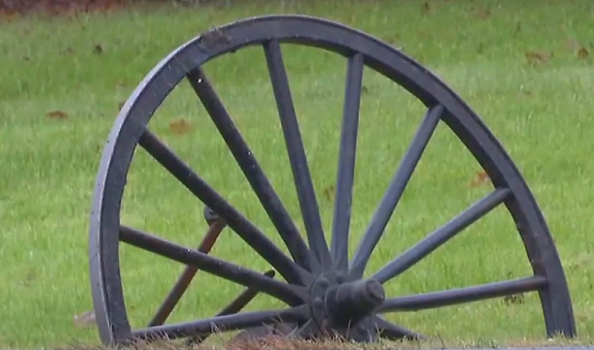 Amish Buggy Wheel Roadside After Crash A buggy wheel lying in the grass at the side of a road after a crash