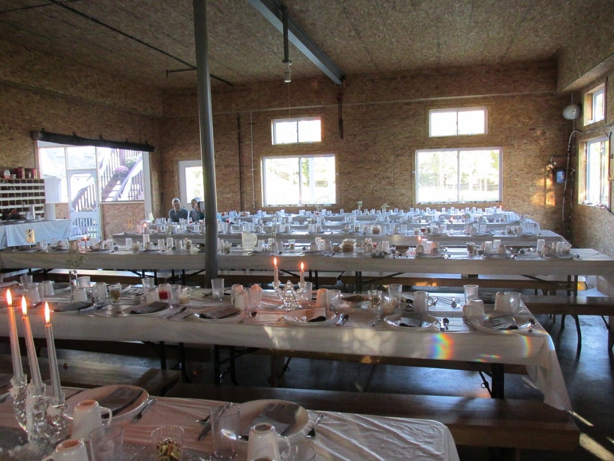 Candlelit tables set in a dining hall for an Amish wedding meal