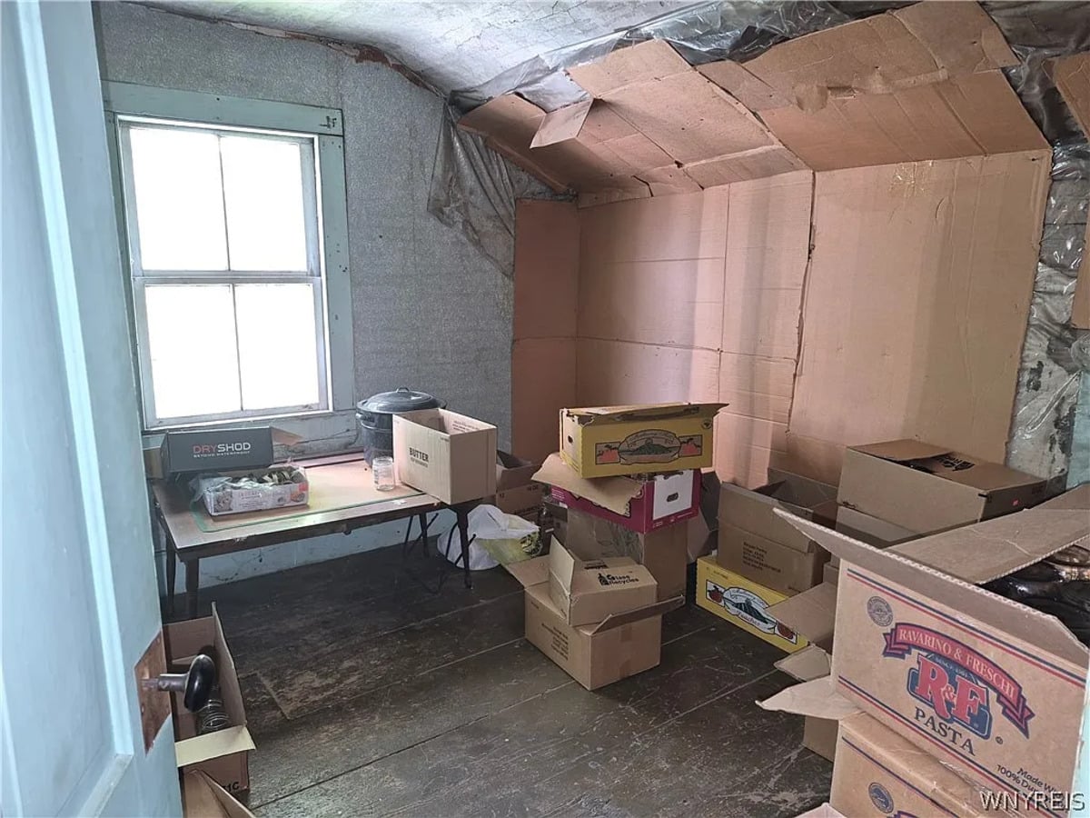 Upper room with flattened cardboard boxes fixed over the wall insulation and boxes across the plank floor