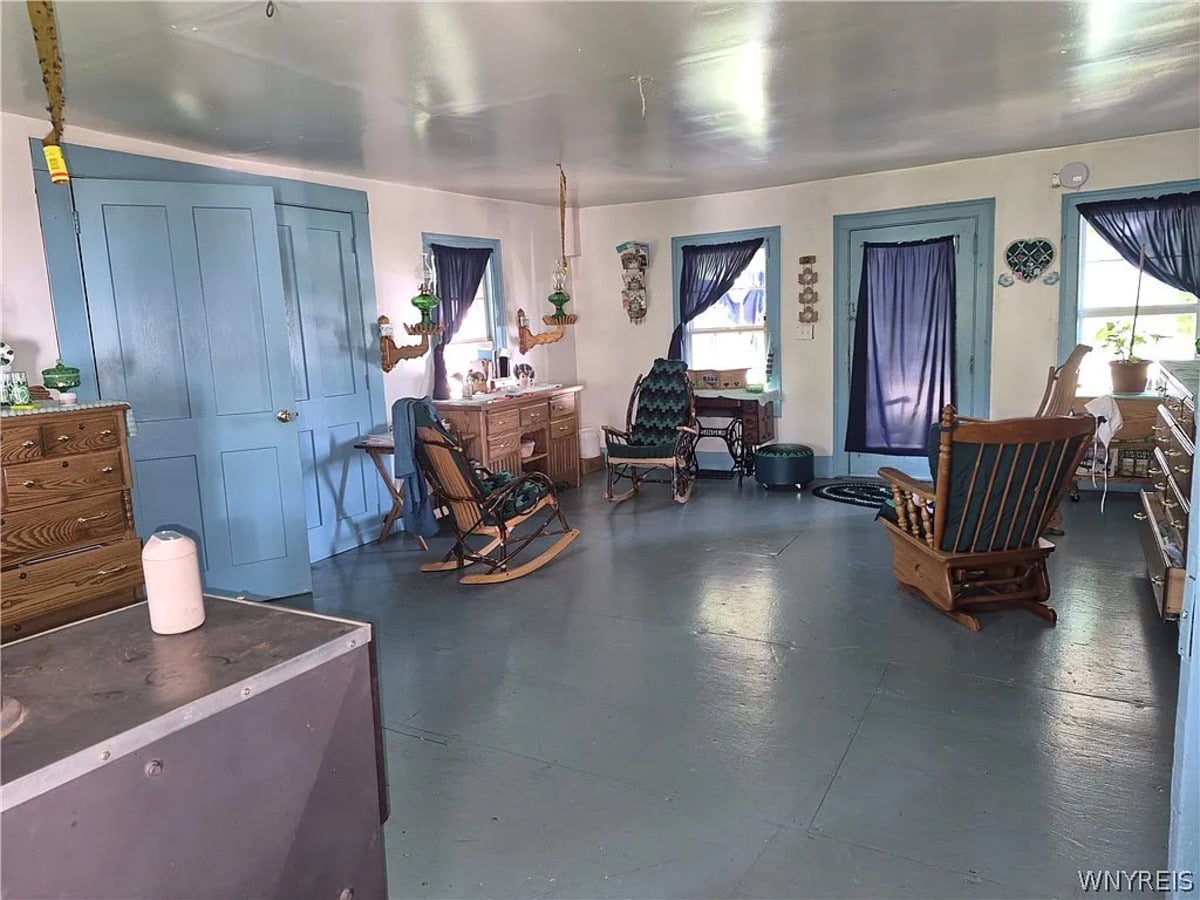 Treadle sewing machine beneath a window in an Amish front room with blue-painted doors