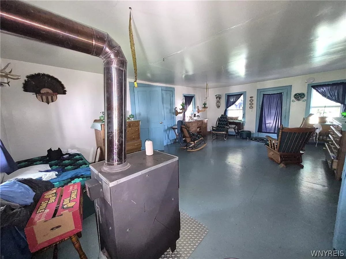 Box wood stove with stovepipe running across the ceiling of an Amish front room