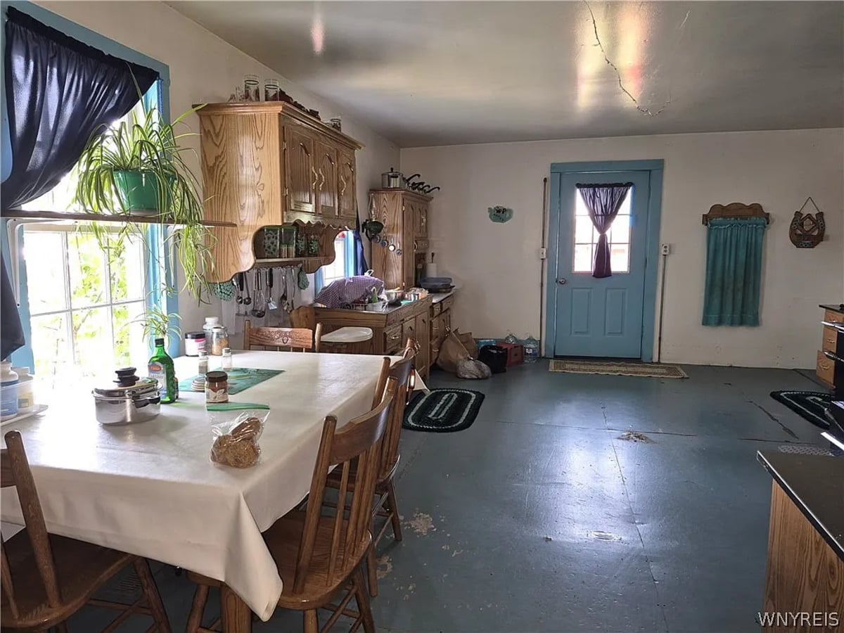 Amish kitchen with a long table under an oilcloth, oak cabinetry, and a spider plant in the window