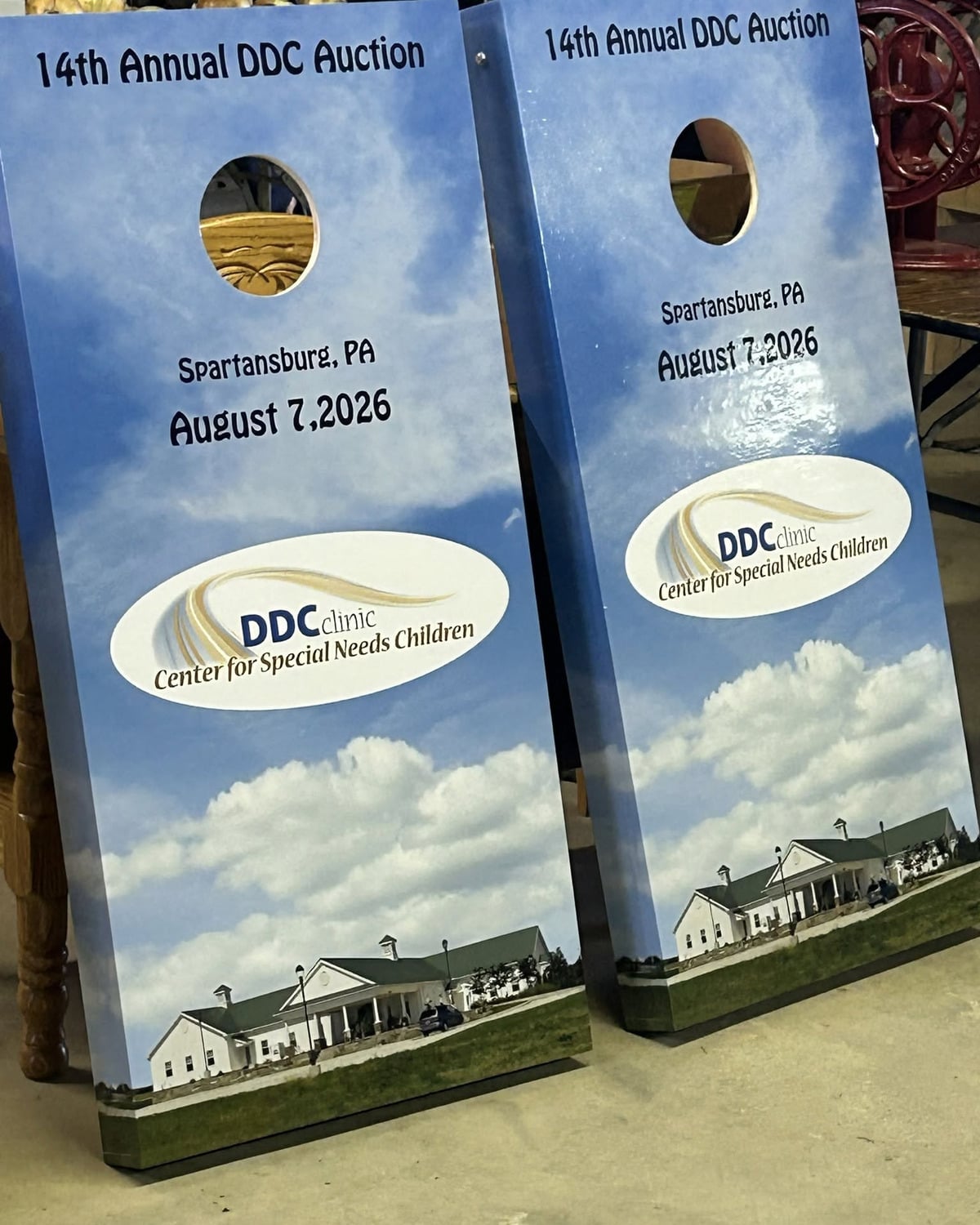 Two cornhole boards printed with 14th Annual DDC Auction, Spartansburg, PA, August 7, 2026