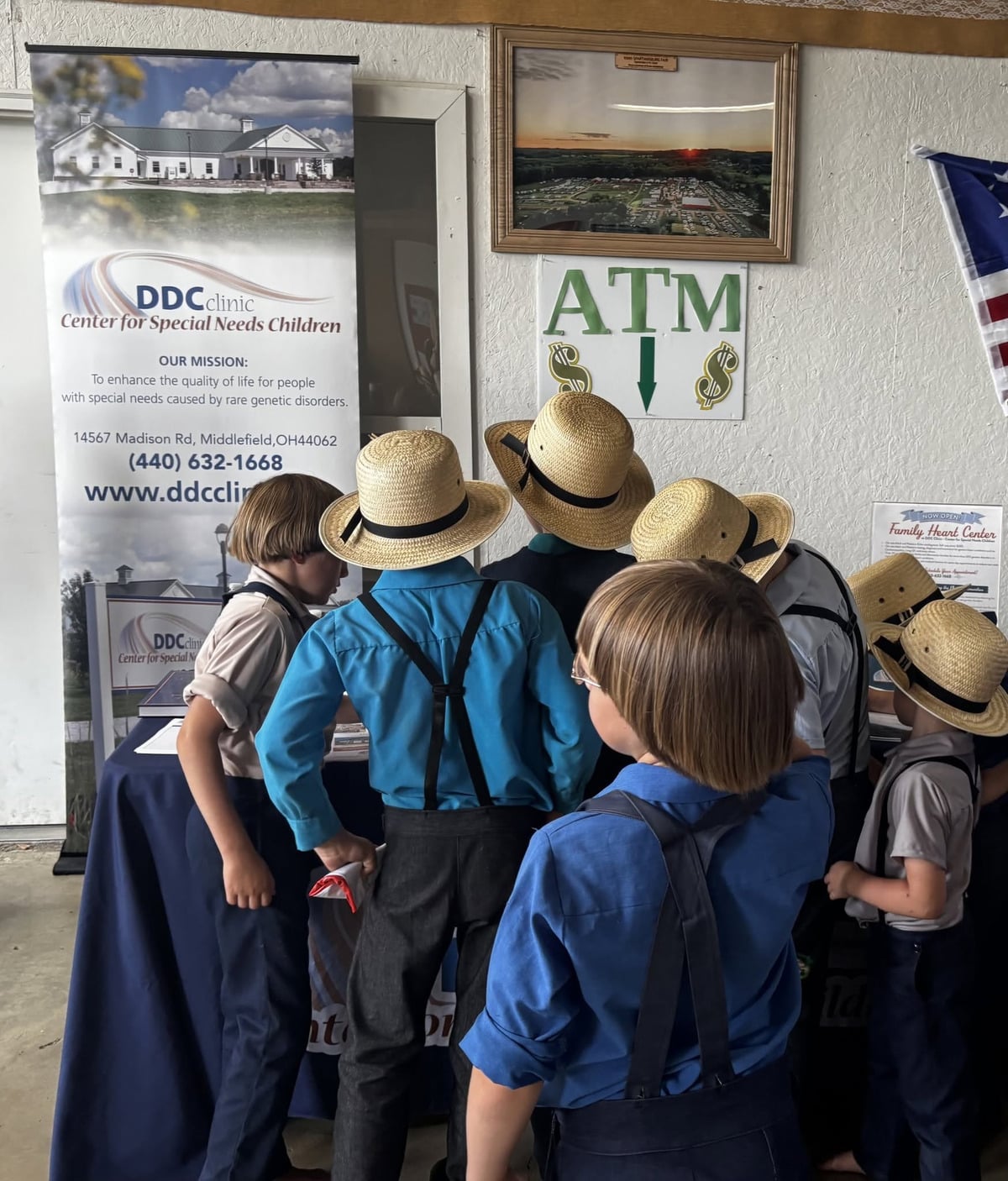 Amish boys in straw hats gathered at the DDC Clinic information table at the Spartansburg auction